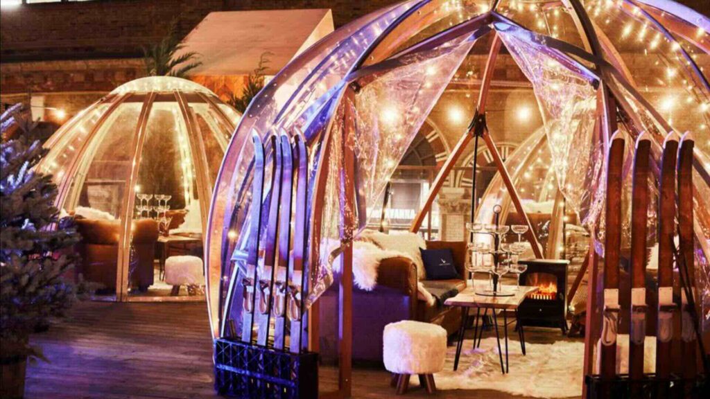 A gorgeous outdoor dining igloo illuminated at night with lights and heating.