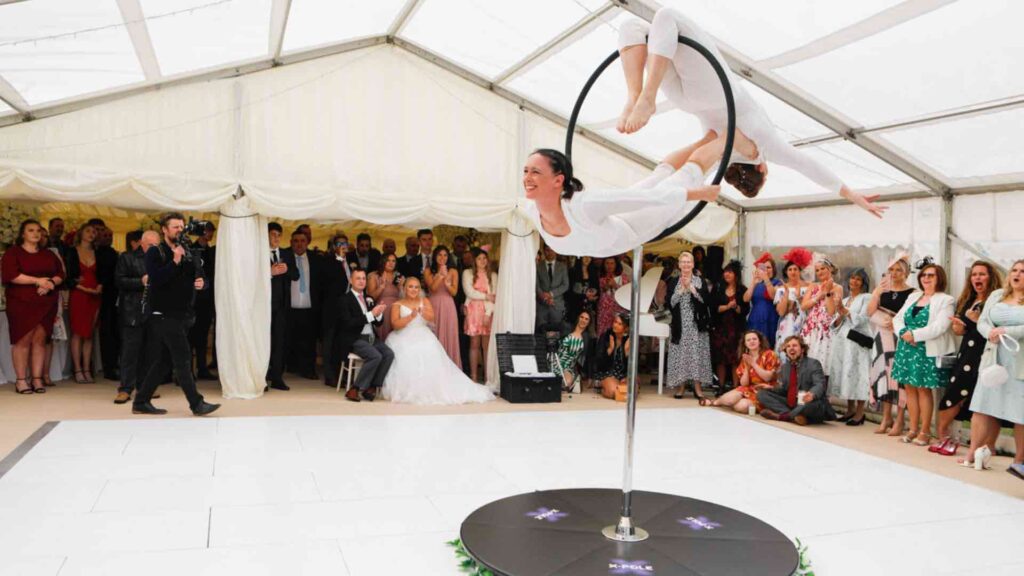 An aerial performance duo doing tricks at an indoor company summer party.