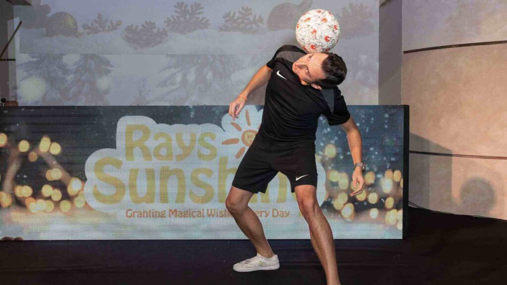A football freestyler balancing a ball on his head.