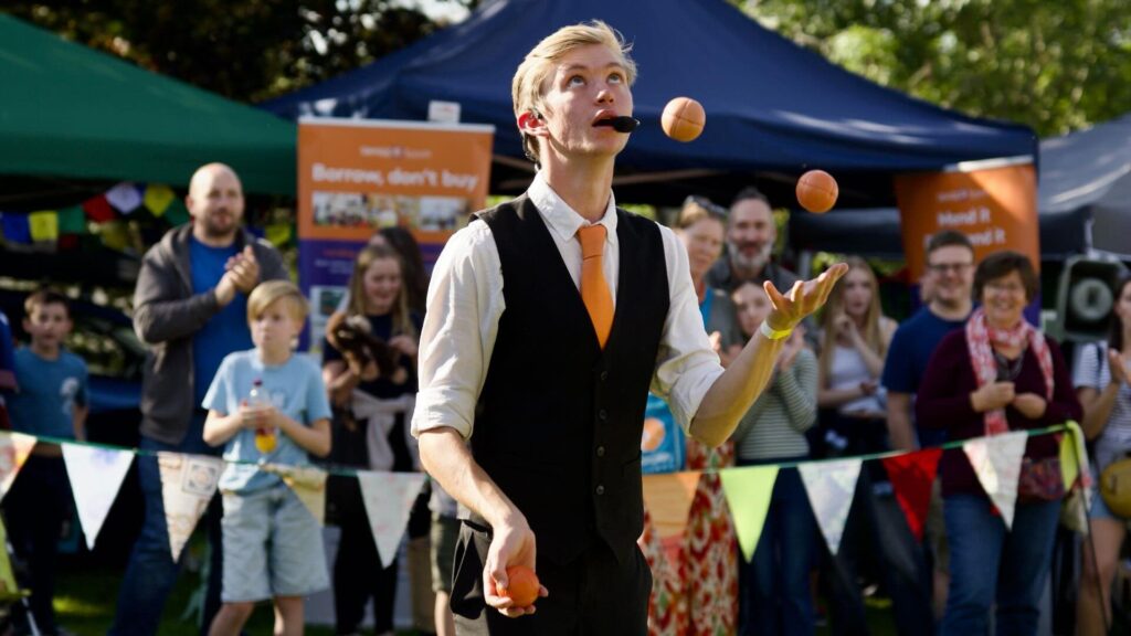 Juggling walkabout performer entertaining crowds at outdoor event.