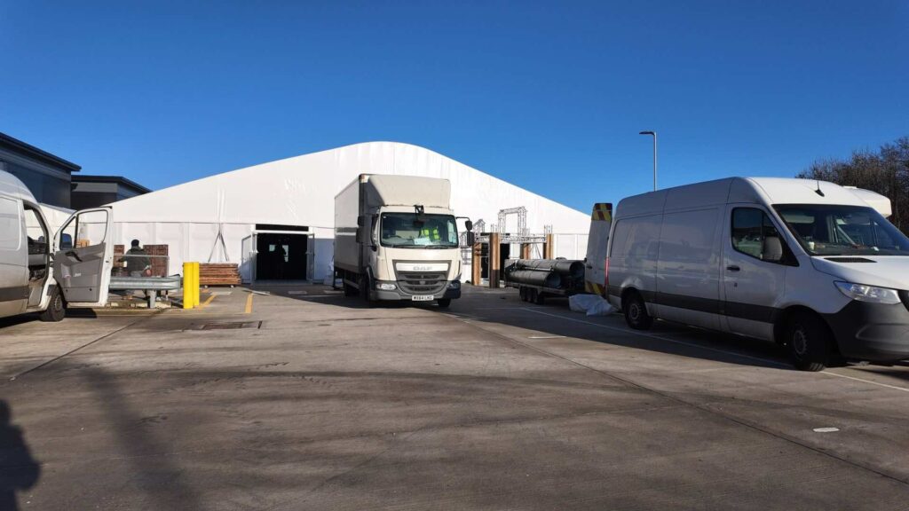 View of carpark with temporary marquee and delivery trucks at Solihull Gymshark HQ.