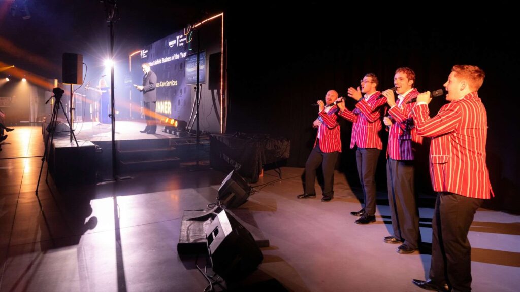 Four vocalists performing bespoke award stings on stage at a luxury awards event.