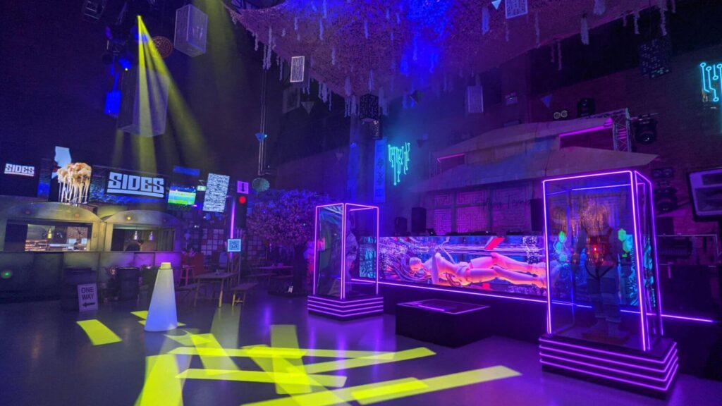Immersive authentic event space with futuristic props and purple and yellow lighting.