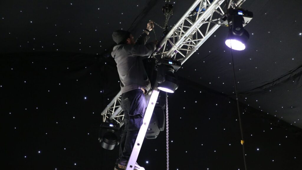 Team setting up lighting and rigging for event installation.