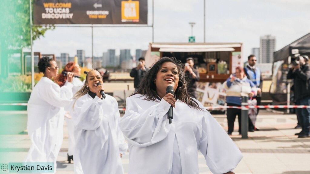 Gospel choir singers performing song at UEL Summer Festival as part of an immersive custom show production.