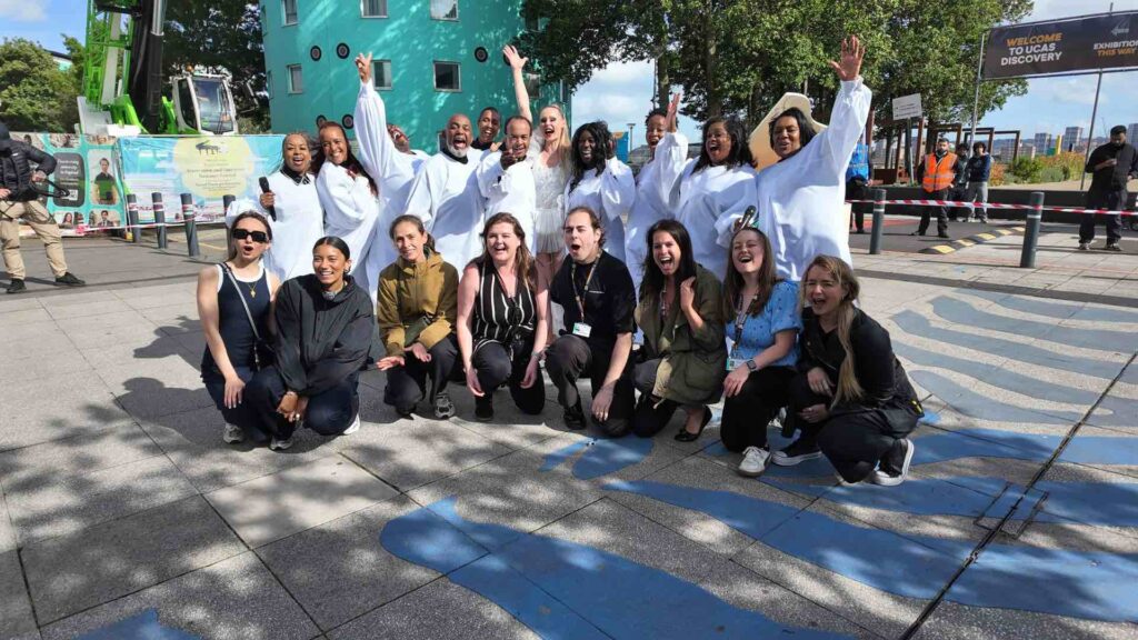 The UEL event team and client posing with gospel choir and aerial pianist post bespoke show.