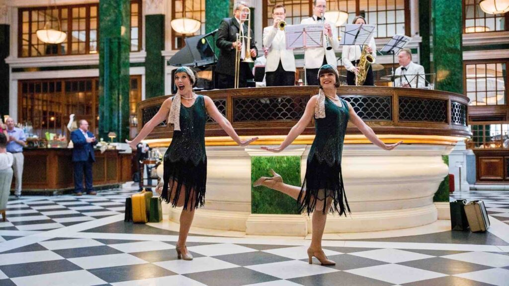 1920s flapper dancers in front of a musical stage.