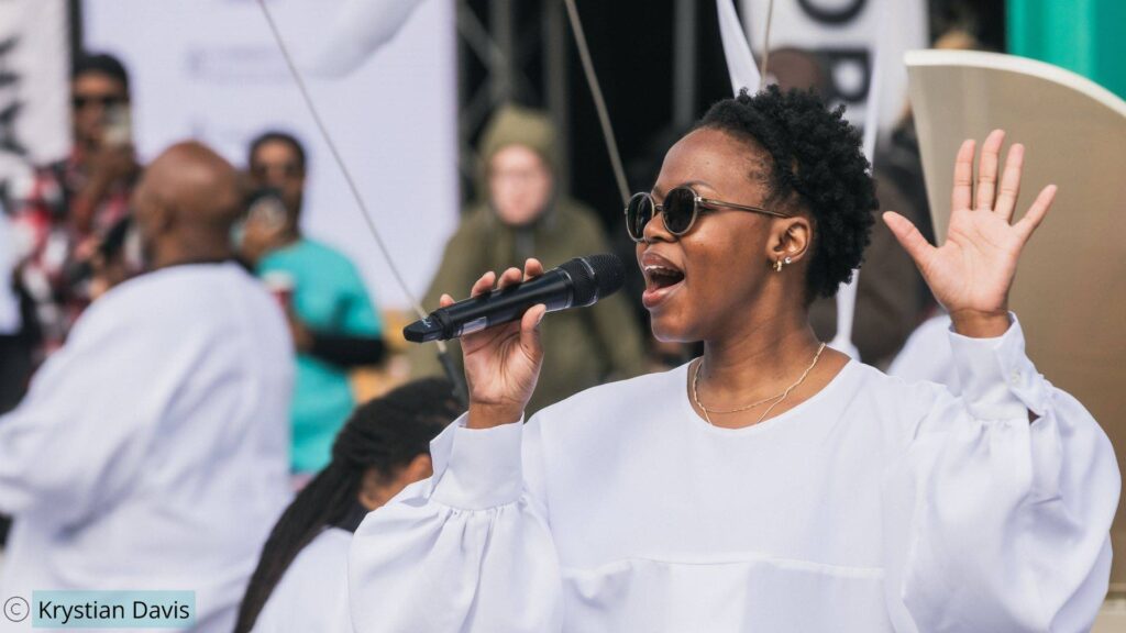 Female gospel singer with her hand in the air performing passionately for a signature custom show production by JCEM.