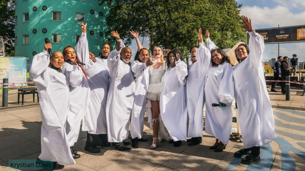 Gospel choir posing with aerial pianist after their bespoke show production at UEL in London.