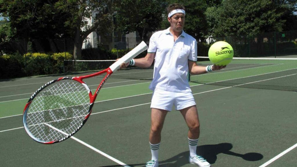 Our Wimbledon party comedy player performing for a crowd on a tennis court.