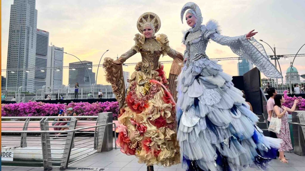 Sun and moon stilt walkers posing for pictures and interacting with people.