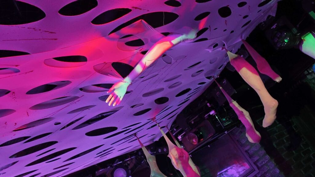 White ceiling webbing with hanging body parts and limb props hanging from ceiling.