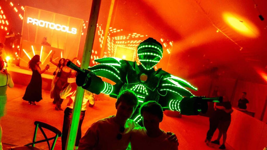 A futuristic themed robot dancer performing with guests enjoying in the background,