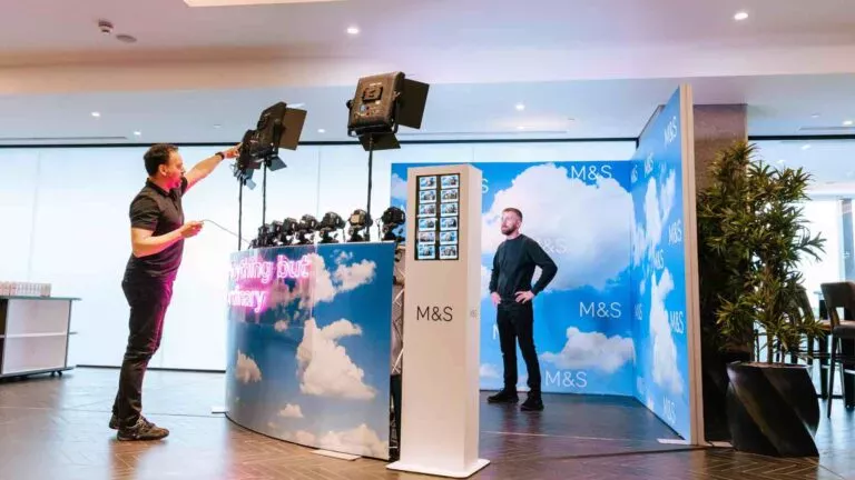 Guests at a custom 3D branded photo installation with neon lettering and floral archway
