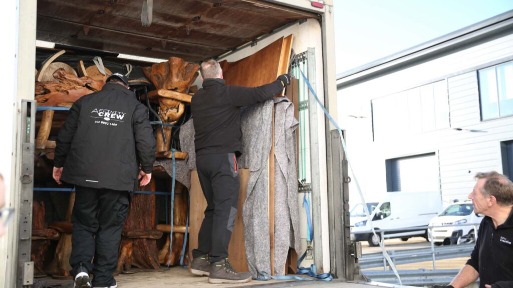 Rustic timber furniture and scenic elements being unloaded on delivery day.