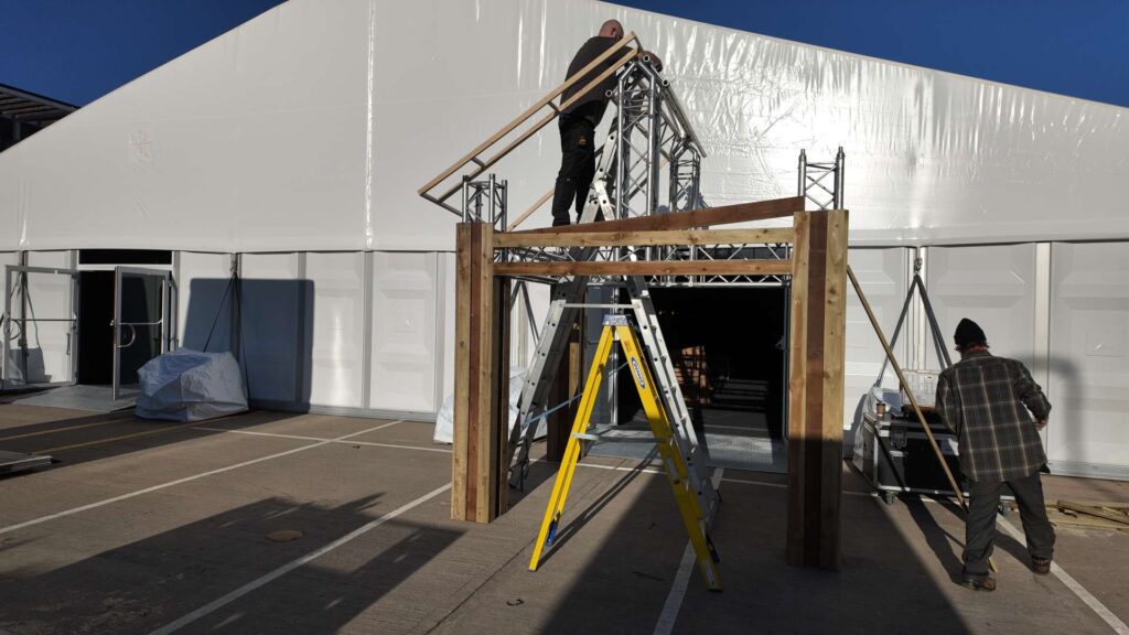 Timber lodge entrance structure under construction during a corporate Christmas venue transformation