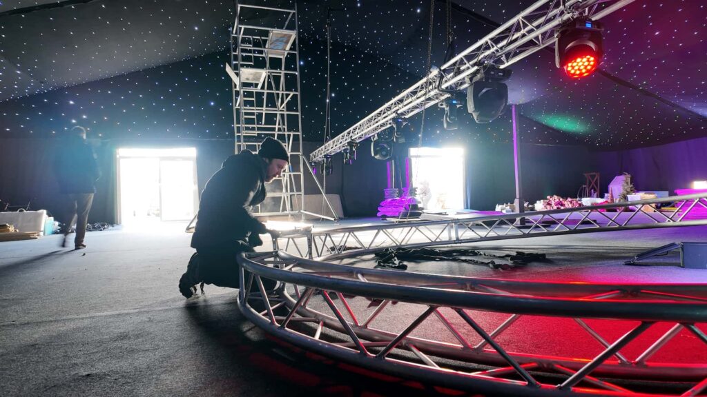 Production crew assembling a circular truss ring during corporate Christmas event rigging