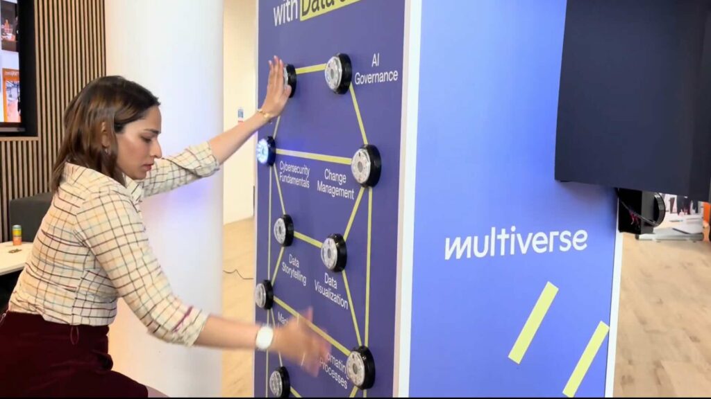 Woman playing a branded batak game wall with lit targets labelled with a company's course topics