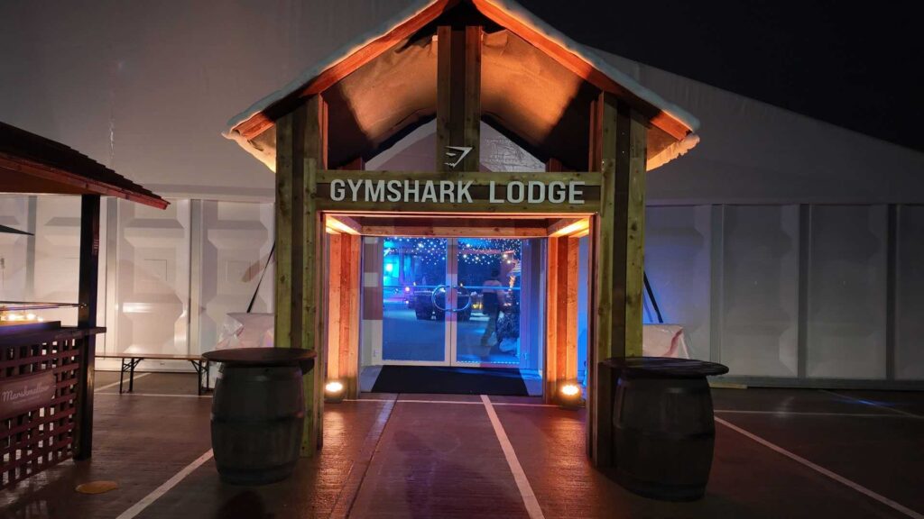 Gymshark Lodge branded alpine entrance with snow-capped roof at a corporate Christmas party.