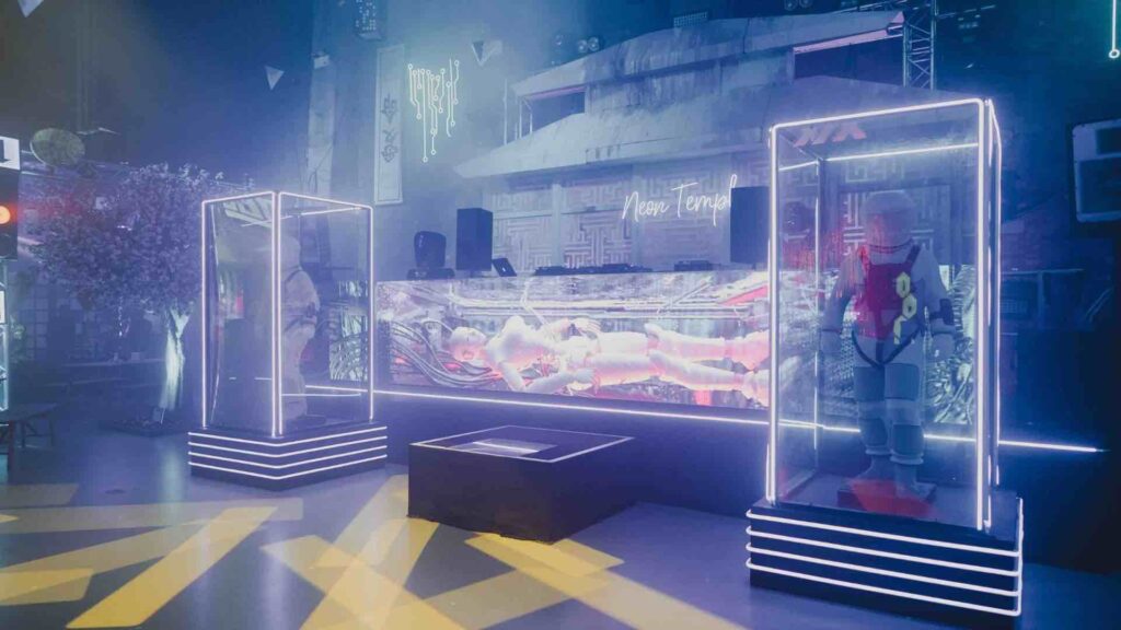 Neon Tokyo themed event set design with illuminated display cases, futuristic costume props and a backlit LED screen.