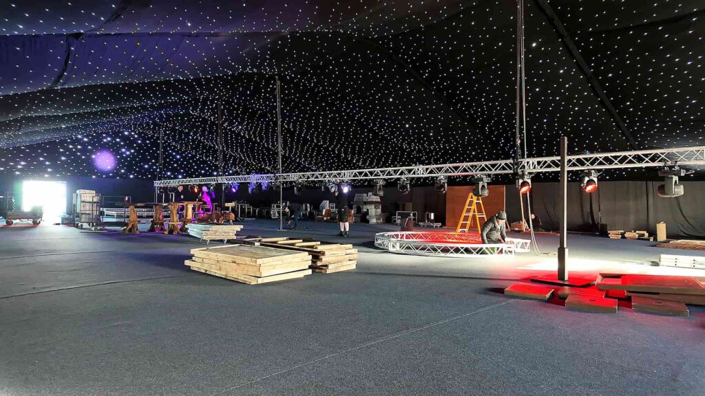 Crew rigging truss and moving lights beneath a starcloth ceiling during a Christmas event build