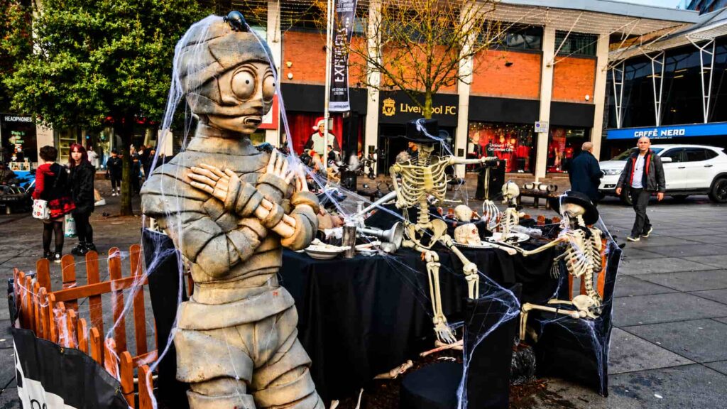 Immersive Halloween installation with a giant mummy character and skeleton banquet scene in a busy public square