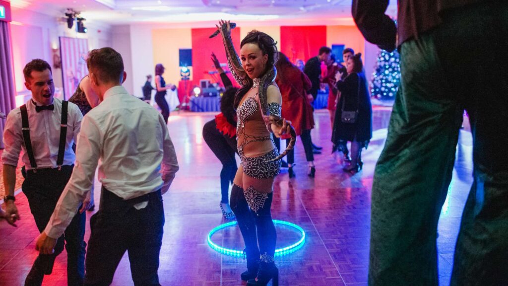 Interactive Christmas entertainer performing with an illuminated LED hoop among guests on the dance floor