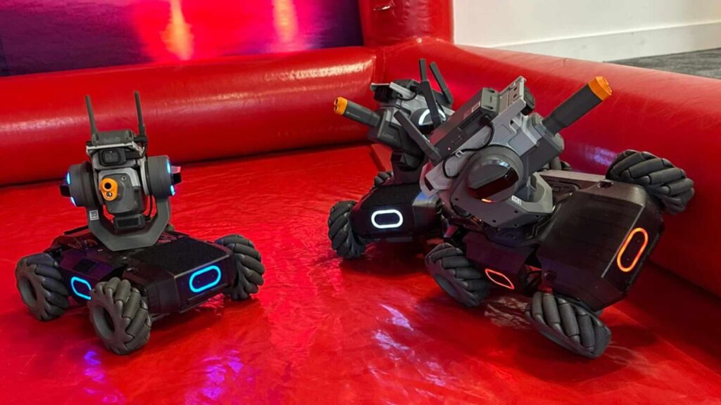 Three grey and black battle robots glowing blue and orange lights.