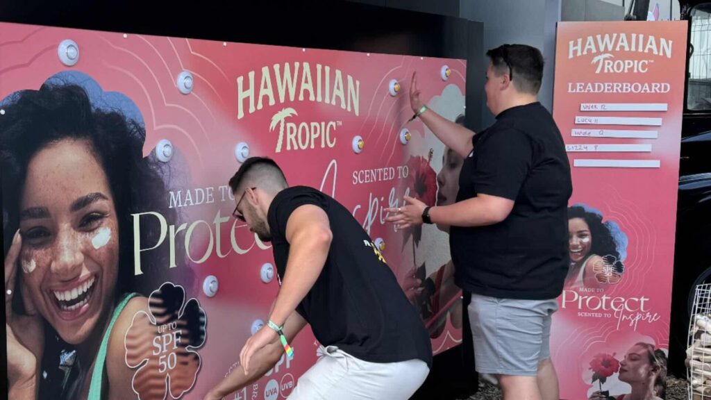 Two players, a pink wall with light-up buttons, and a handwritten leaderboard.