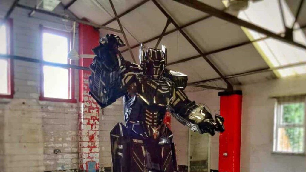 Tall black and silver robot costume with angular armour plating and one arm raised.