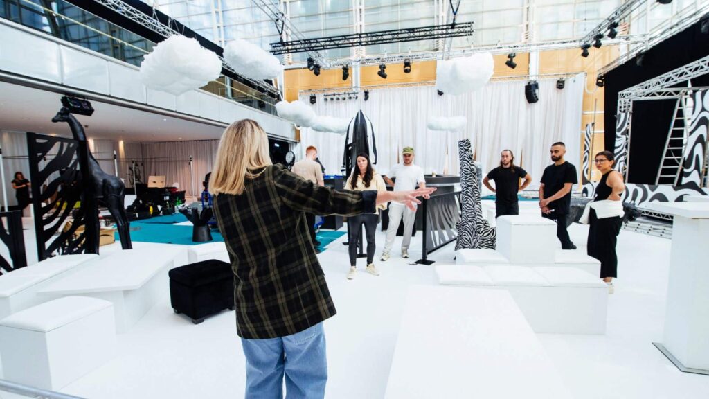 Julia Charles briefing the event team on a white set build with hanging cloud props during set-up