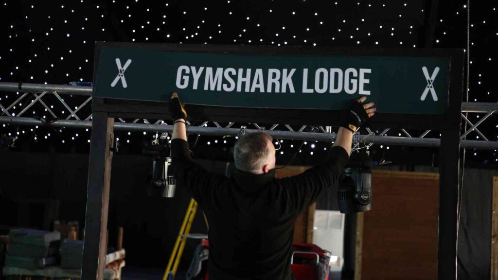 Event supplier installing the Gymshark Lodge sign during the Christmas event build
