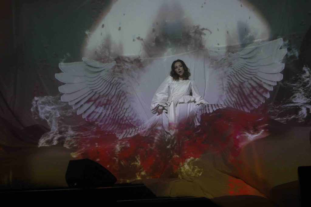 Singer in a 3D projection-mapped dress at the Red Mix product launch at Tobacco Dock