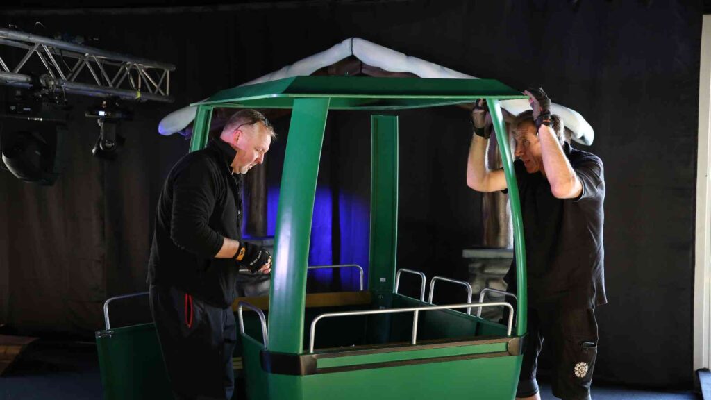 Two event production suppliers assembling a green cable car during the Gymshark Christmas event build