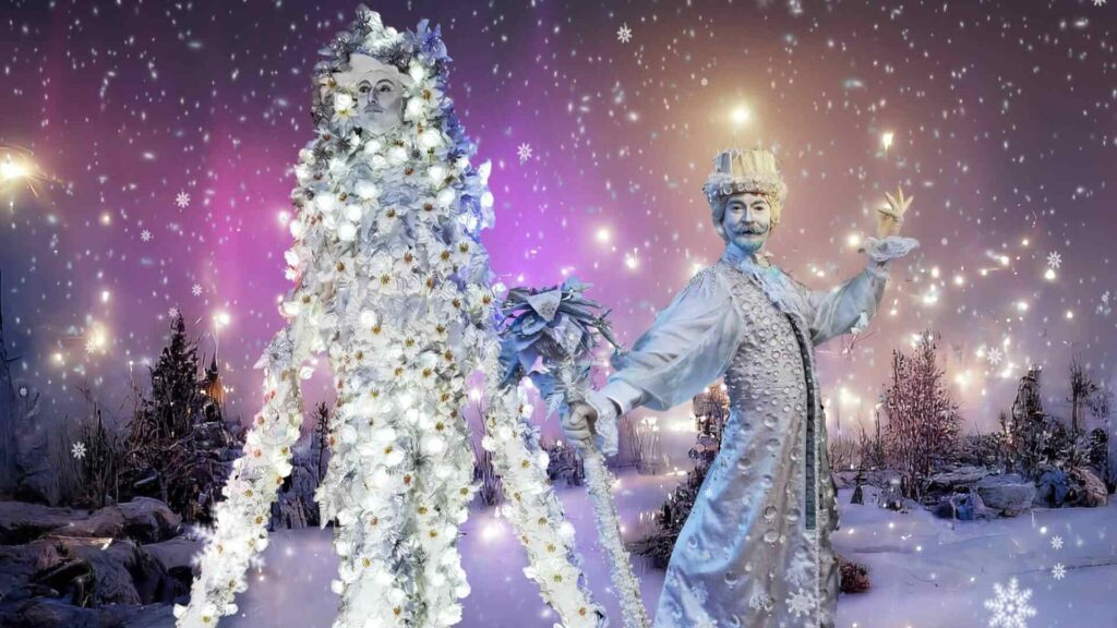 Aurora in a costume of glowing white flowers beside Jack Frost in a silver coat holding a frosted staff, in a snowy scene